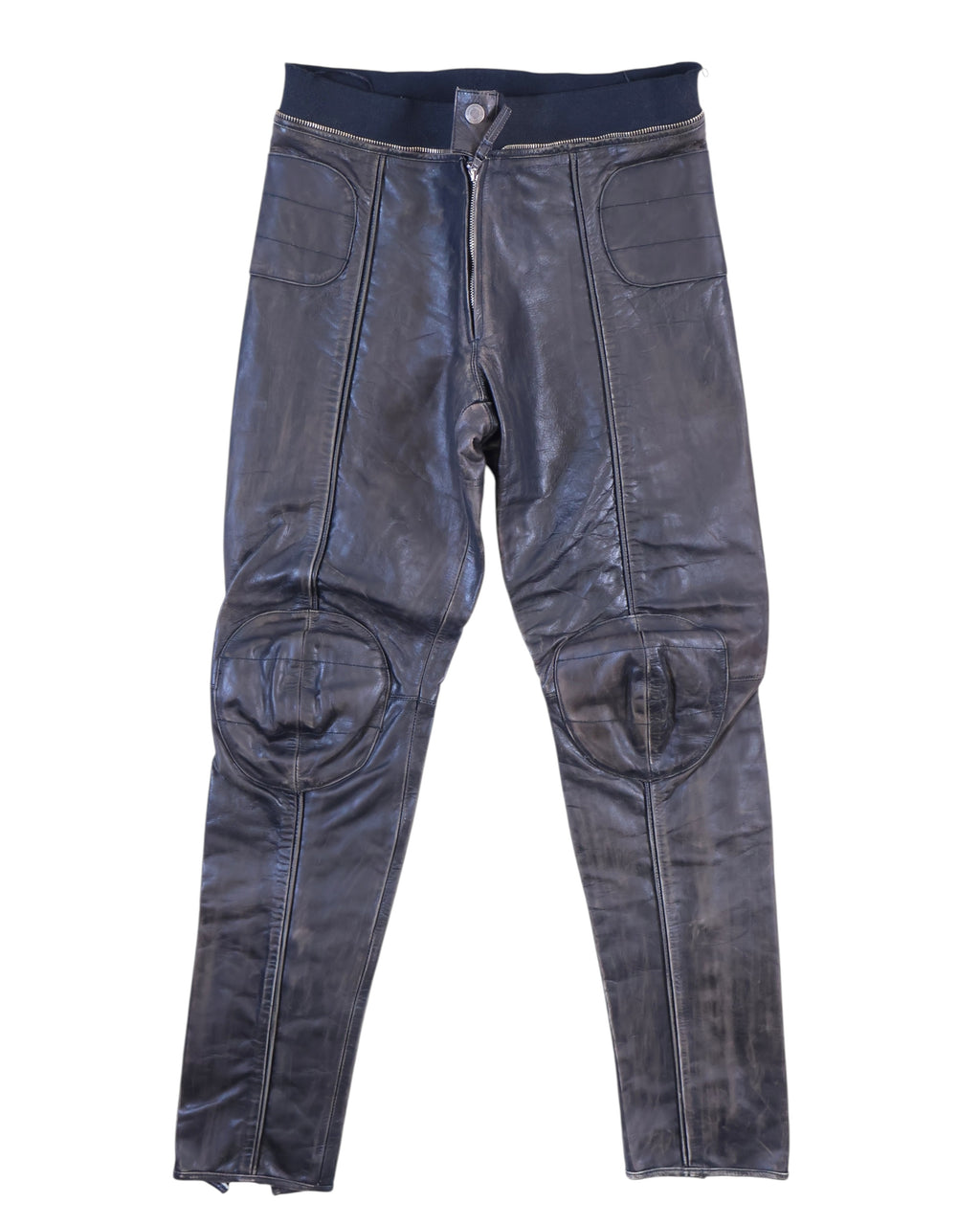 Vintage 1990s Jean Paul Gaultier black leather pants/trousers with moto biker detailing—padded rounded knees, paneled seams, front zip with snap and rib-knit waistband. Slim tapered leg; high-end, rare and unique piece laid flat on white.
