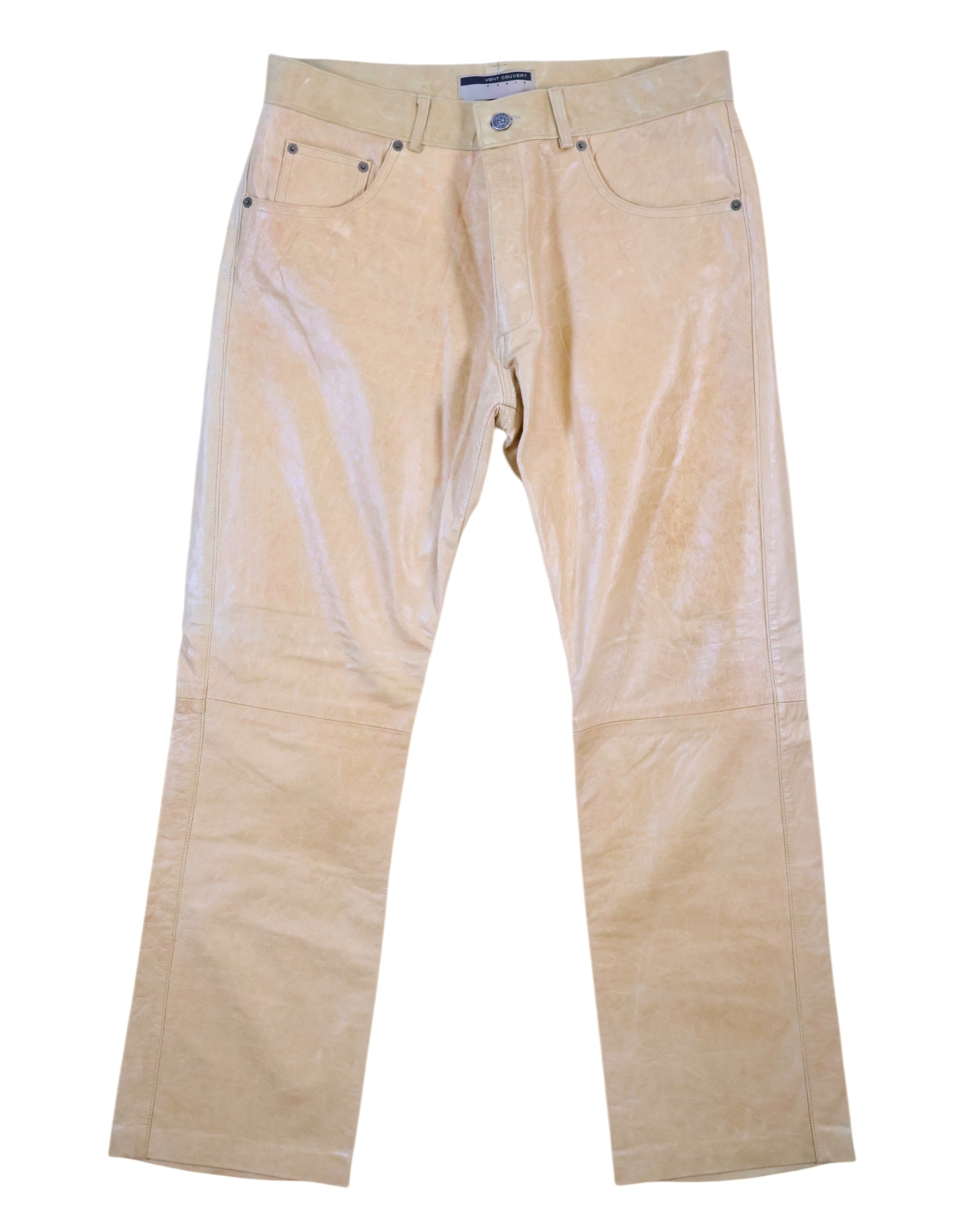 A pair of beige calfskin leather pants with a front zipper and button closure, displayed against a white background. Vintage Vent Couvert beige calfskin leather pants/trousers with a smooth glossy finish; mid-rise straight leg, five-pocket jeans styling with belt loops, button front and subtle knee seams. High-end, luxury, rare piece laid flat on white.