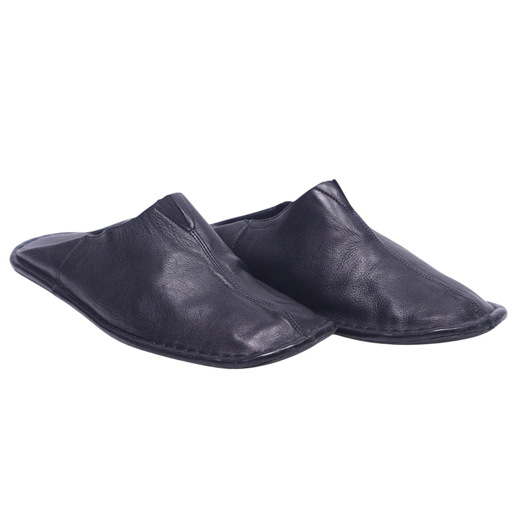 A pair of black leather slippers. Atika black leather slippers/mules in a backless, minimalist slip-on silhouette with soft grained leather, center seam and flat flexible sole; artisanal, luxury, rare and unique house shoes.