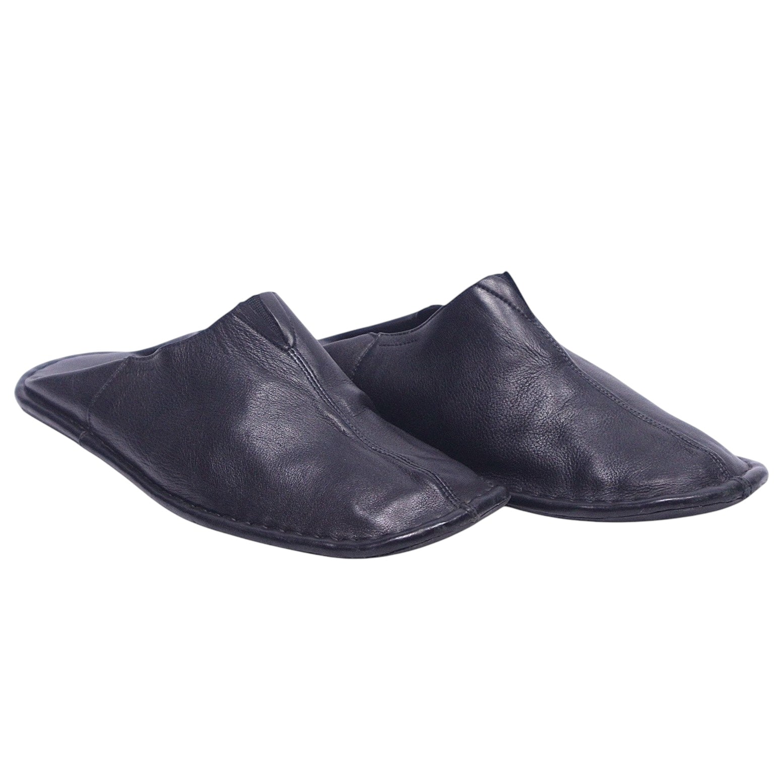 A pair of black leather slippers. Atika black leather slippers/mules in a backless, minimalist slip-on silhouette with soft grained leather, center seam and flat flexible sole; artisanal, luxury, rare and unique house shoes.
