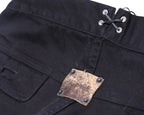 Back-waist detail of black Voyage Mazzilli Michielsens jeans featuring grommet lacing and a distressed square leather logo patch riveted to the waistband, with clean tonal stitching on twill denim.