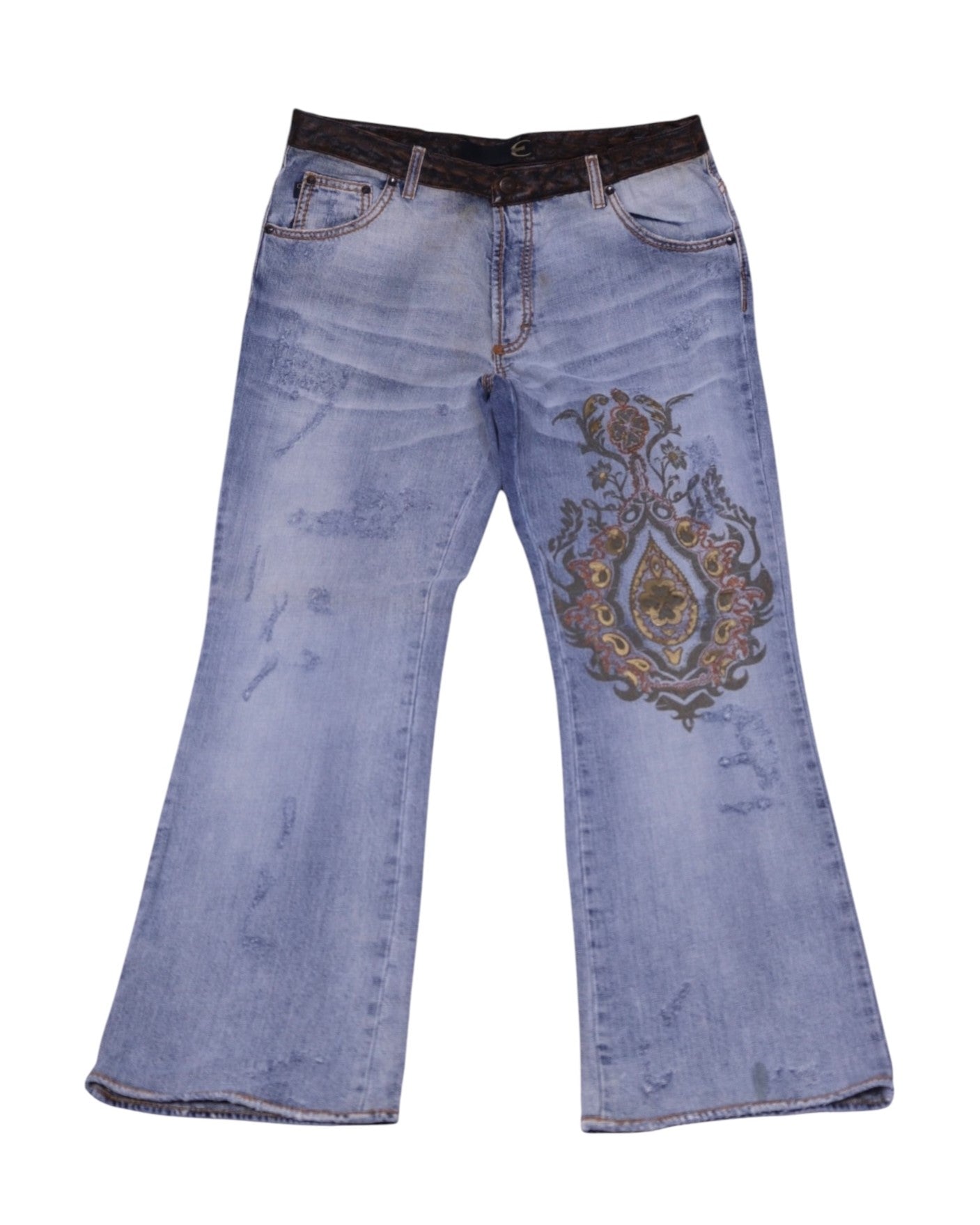 A pair of Roberto Cavalli jeans with a metallic floral design on the right leg, laid flat on a white background.Roberto Cavalli light-wash denim jeans with a relaxed flared leg, five-pocket design and belt loops. Large metallic baroque print on the thigh with gentle fading; vintage designer, rare statement pair.