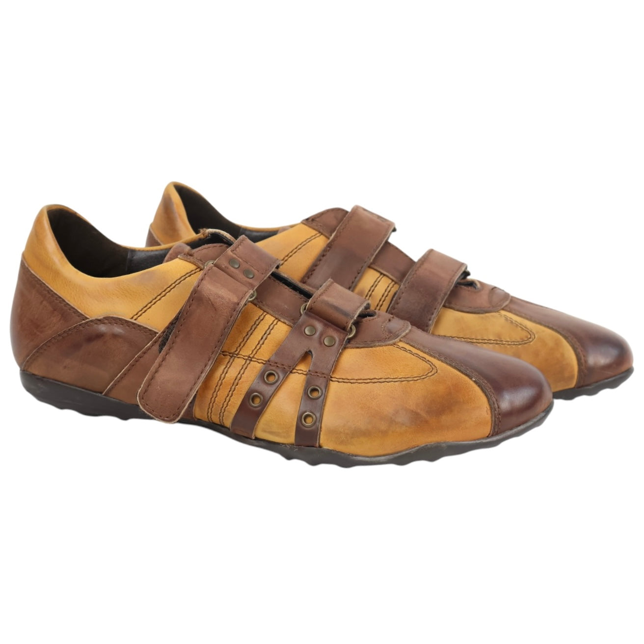 A pair of brown leather Kenneth Cole sneakers with Velcro straps and a chunky sole. Kenneth Cole brown leather low-top sneakers with two-tone tan/brown panels, Velcro strap closures, stud details, and rubber sole.