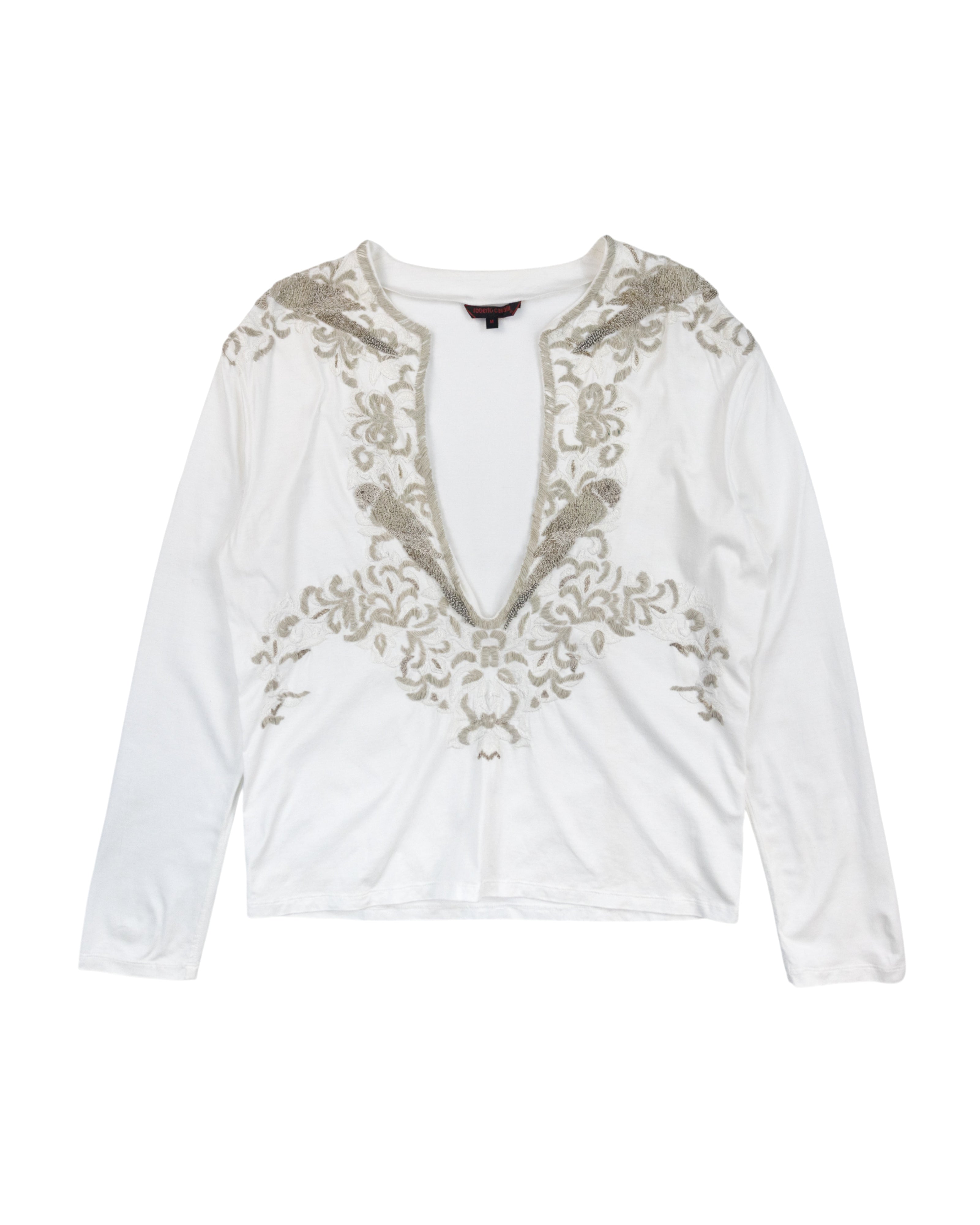 Roberto Cavalli White long-sleeve top with  a deep V-neck and with embroidery on a white background. Roberto Cavalli white/ivory cotton jersey long-sleeve top; dramatic deep V-neck, ornate baroque embroidery in metallic thread, soft drape; slim/regular fit, unisex styling; perfect with denim, tailoring or night-out looks; boho/glam/Y2K/Italian baroque; Italian luxury house known for opulent prints and craftsmanship; rare vintage piece.