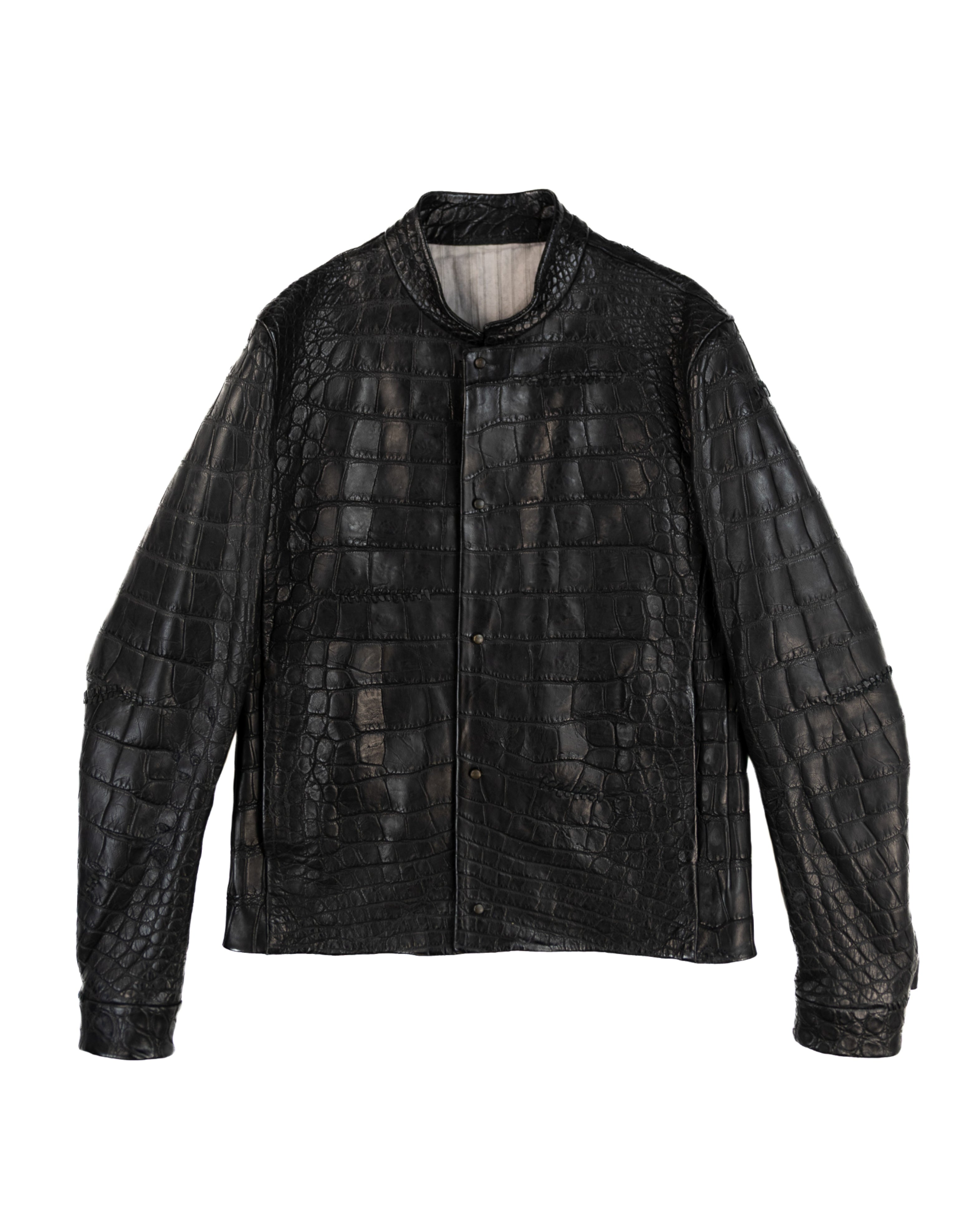 Isaac Sellam for L’Éclaireur black/ebony crocodile leather jacket; exotic croc-skin panels, collarless stand neck, snap-button front, straight hem, sculptural sleeves, clean seaming; matte/antique metal hardware; regular fit, unisex; pairs with denim, tailoring, streetwear; avant-garde, minimal, luxury, runway, collectible; brand context: French artisanal designer from Paris in collaboration with the famed Paris concept store; rare limited piece.