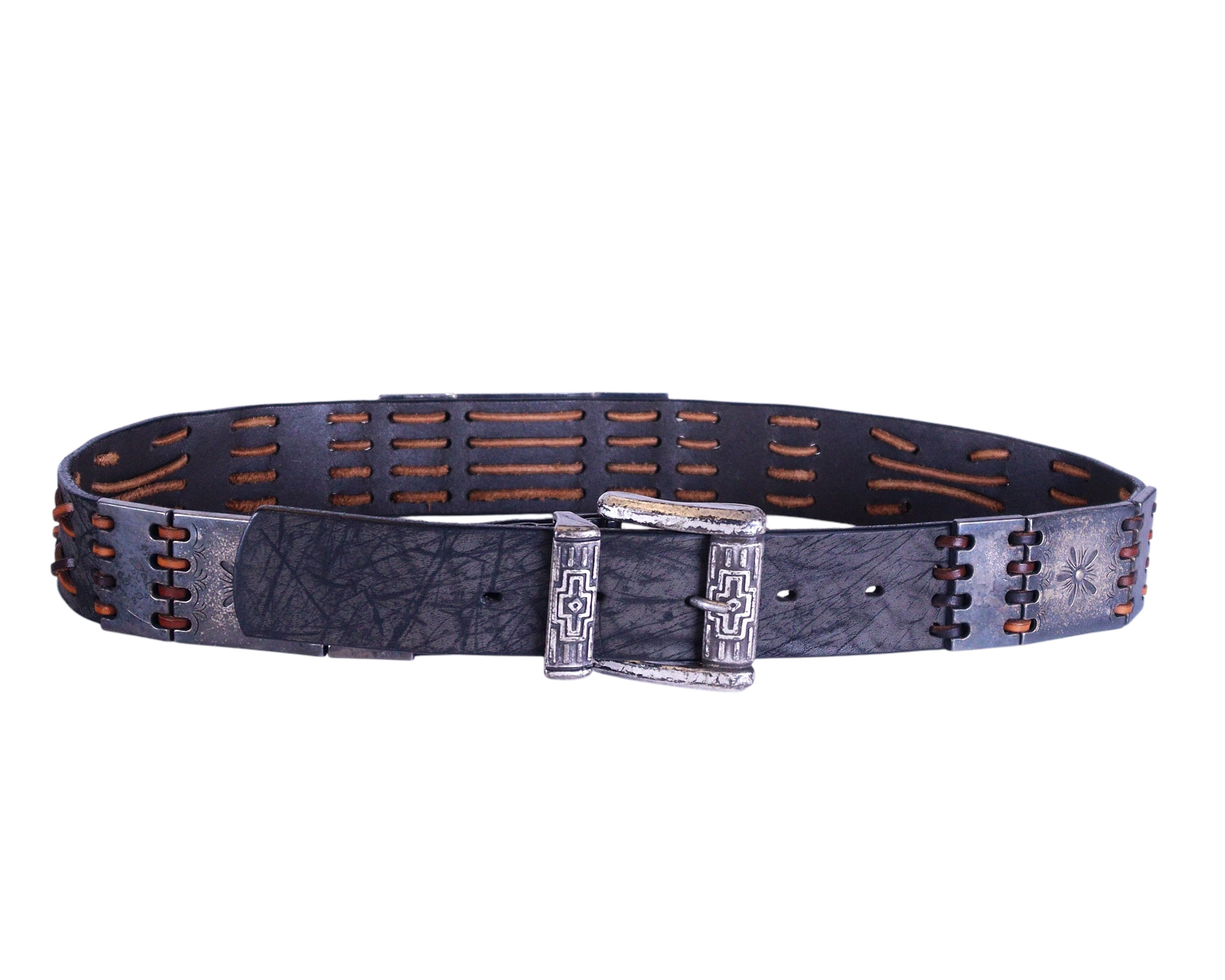 A black leather belt with metallic pieces and a silver buckle, featuring intricate stitching and designs. Sa-G.Ja artisanal German leather belt; black/charcoal distressed crackle cowhide; wide strap with slotted cutouts and contrast tan whipstitch/lacing; antiqued silver-tone engraved buckle, single-prong; rustic hand-finished patina; adjustable multi-hole fit; handcrafted/small-batch indie German leatherwork; unisex; western/rock/goth vibe; great with jeans, trousers, or tailoring; premium artisan quality