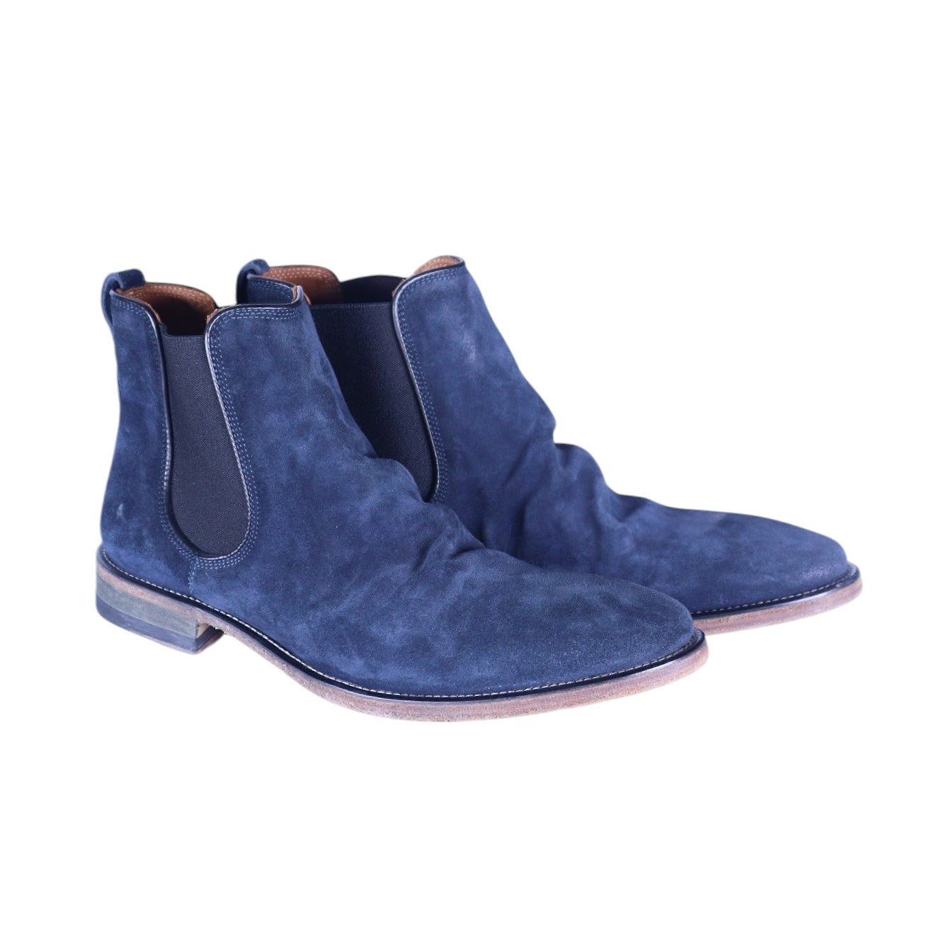 A pair of blue suede leather Chelsea boots with a low heel and elastic side panels. John Varvatos men’s navy blue suede Chelsea boots with elastic side panels, pull tabs, almond toe, and low stacked heel.