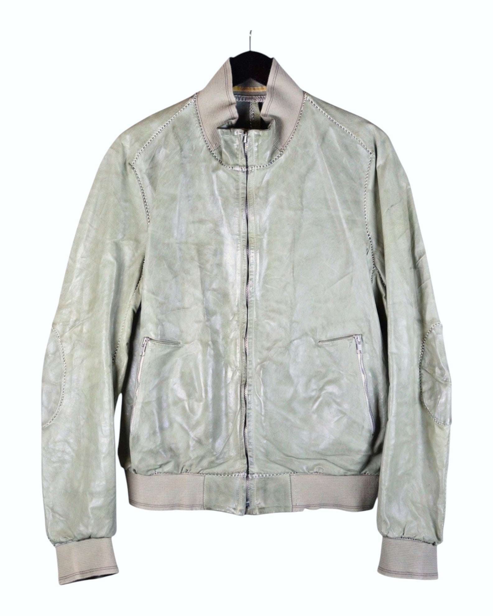 A green leather jacket with a mandarin collar, zipper front, and elastic cuffs, Vintage Carol Christian Poell S/S 2005 sage-green leather jacket—archival avant-garde bomber/blouson with rib-knit collar, cuffs and hem; front zip, zipped hand pockets, articulated elbow seam details, tonal top-stitching; washed pale olive/sage patina, supple genuine leather; Italian/European artisanal construction from the cult Austrian-born designer; unisex, rare collector piece, perfect for layering, streetwear to tailoring.