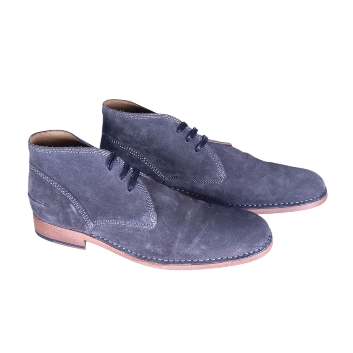 A pair of gray suede leather chukka boots with lace-up closure on a white background. John Varvatos men’s gray suede chukka boots with three-eyelet lace-up, round toe, contrast stitched welt and low stacked heel.
