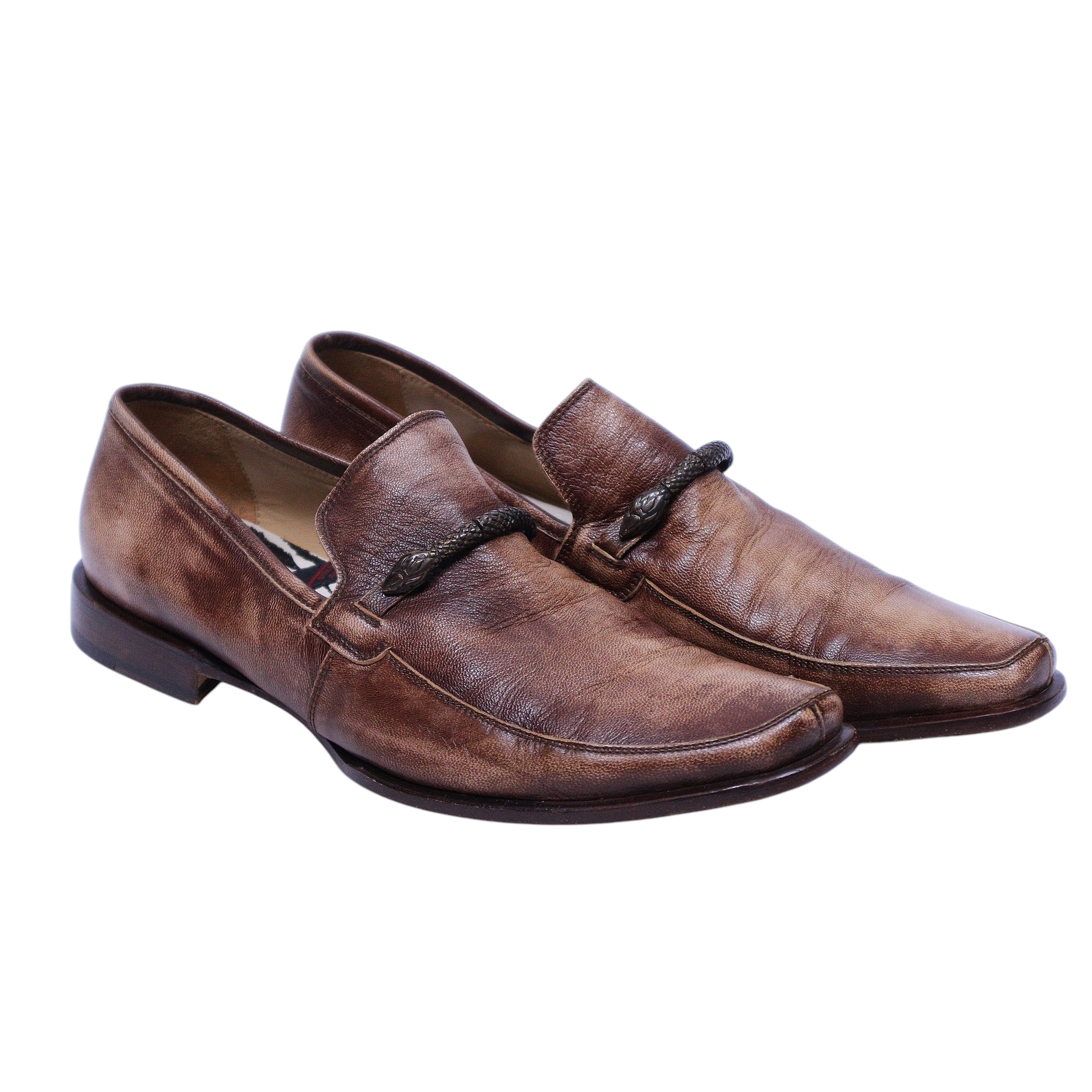 A pair of brown leather men's loafers with a metal snake ornament. Roberto Cavalli brown leather loafers with a burnished finish, square-apron moc stitching and a metal snake bit across the vamp. Slip-on, low-heel dress shoes—vintage, luxury, rare.