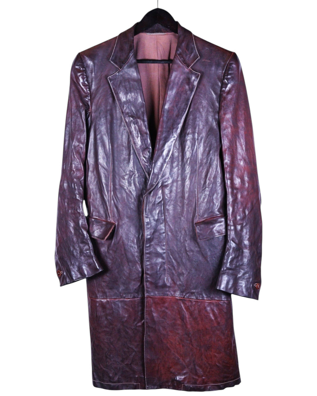 A long leather burgundy coat with a notched lapel, chest pockets, and a hem reaching at least knee-length. Carol Christian Poell burgundy/oxblood maroon leather long coat; notched lapels, single-breasted button closure, flap pockets, paneled build, wrinkled/object-dyed patina; longline overcoat fit, unisex; great over tailoring, denim, boots; style tags: avant-garde, artisanal, runway, archive, minimal; season AW04/05; brand context: Italian luxury atelier by Austrian-born designer, experimental small-batch