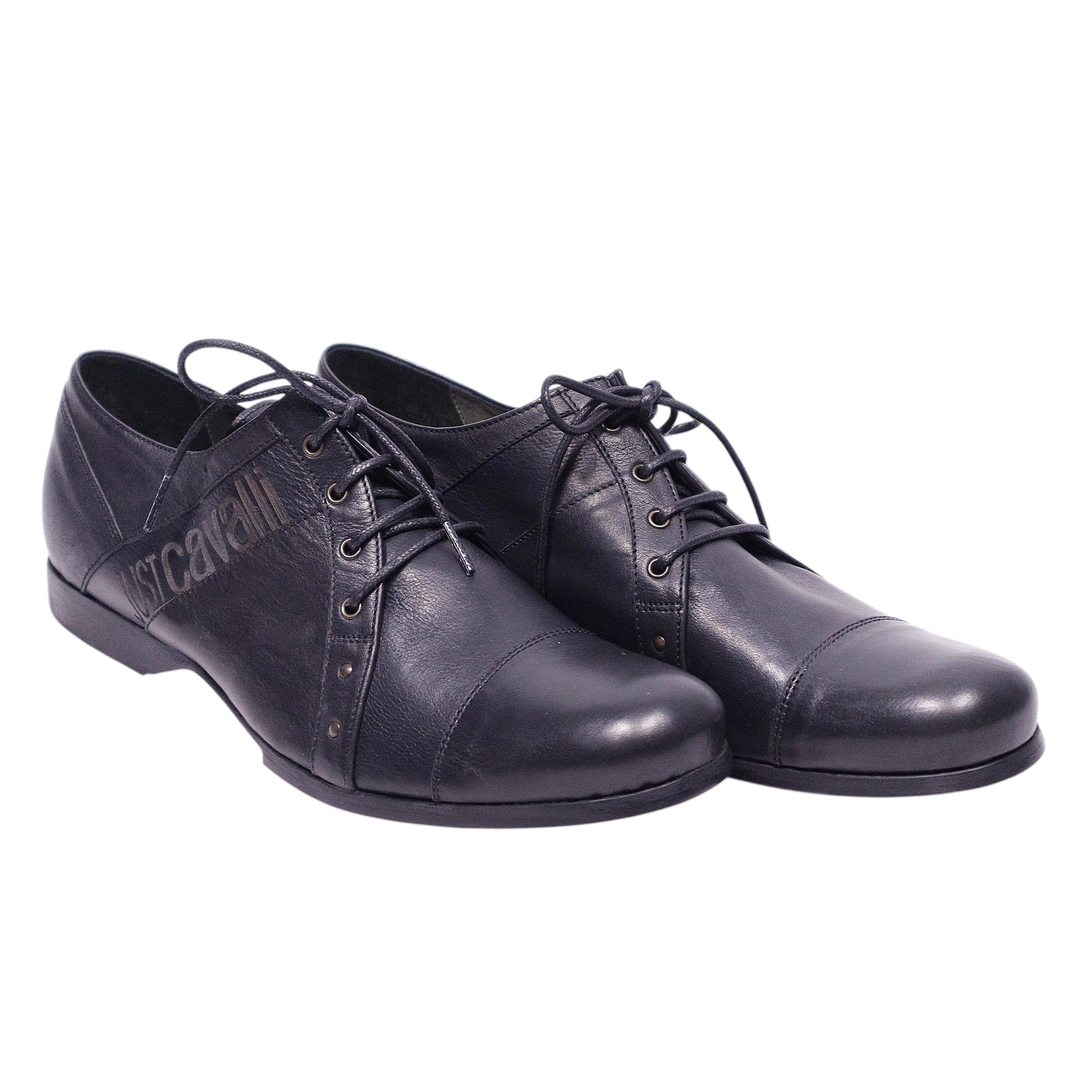 A pair of black Just Cavalli leather oxford shoes with lace-up closure. Just Cavalli black leather Oxford shoes with cap toe, lace-up closure, side logo panel, subtle stud accents, and low-profile sole.