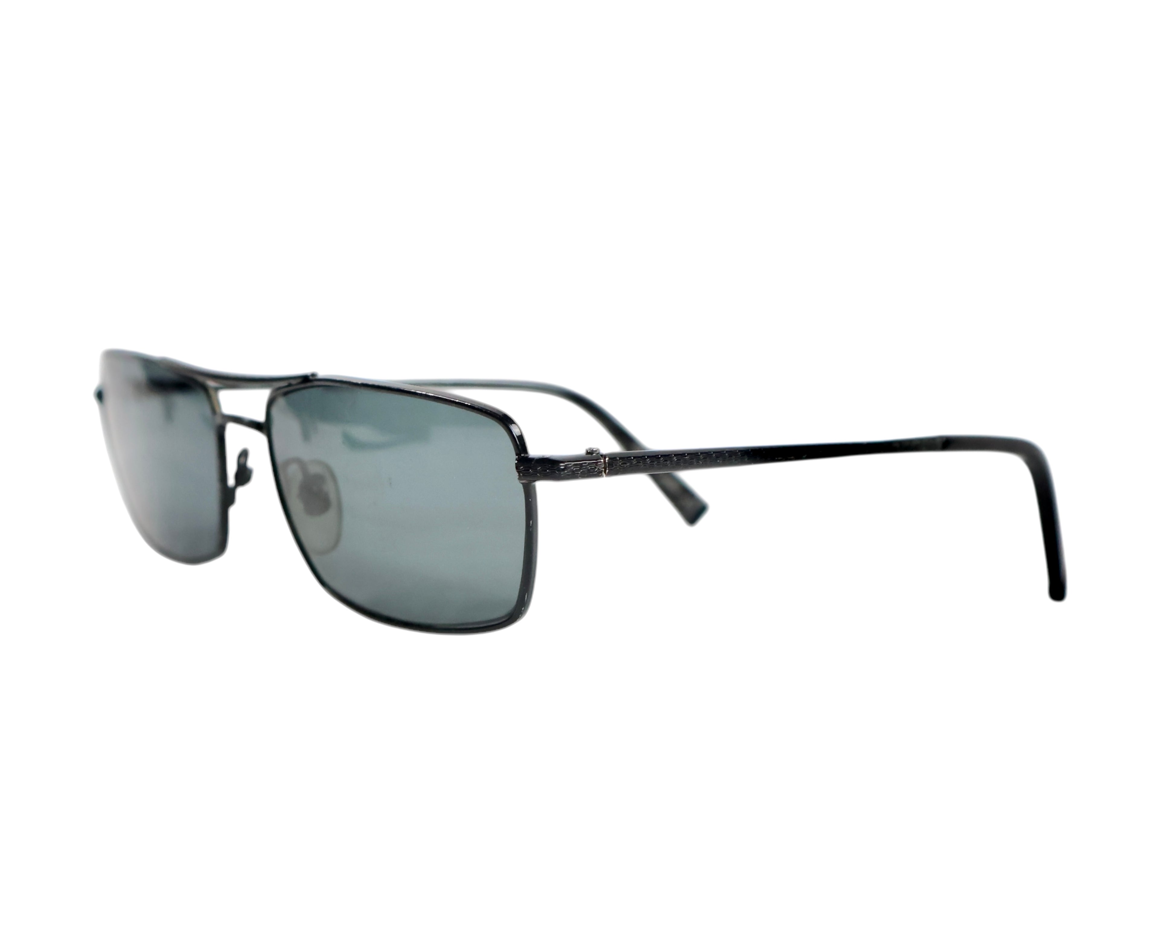 A pair of John Varavatos sunglasses with a metal frame and dark lenses. John Varvatos V116 sunglasses in gunmetal/black metal; slim rectangular/navigator frame with smoke-grey lenses, etched temples, saddle bridge and adjustable nose pads; lightweight UV-shielding eyewear; unisex; pairs with leather jackets, denim, tailoring; tags: rock, indie, minimalist, retro; brand context: American luxury label with rock-and-roll heritage; vintage/limited.