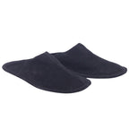 A pair of black suede leather slippers. Atika black suede leather slippers/mules in a backless slip-on silhouette with center seam, soft suede upper and hand-stitched edge on a flat sole; vintage, luxury, rare piece laid flat on white.