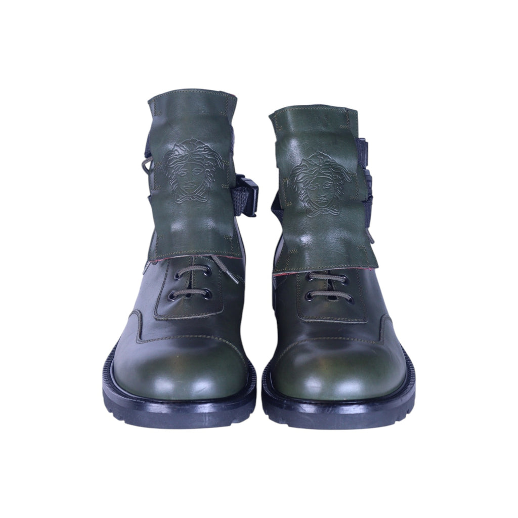 A pair of green leather boots with a Medusa head design on the side, lace-up front, and a chunky sole. Versace green leather combat boots with oversized tongues embossed with the Medusa head, lace-up fronts, side buckle straps, and chunky black soles.