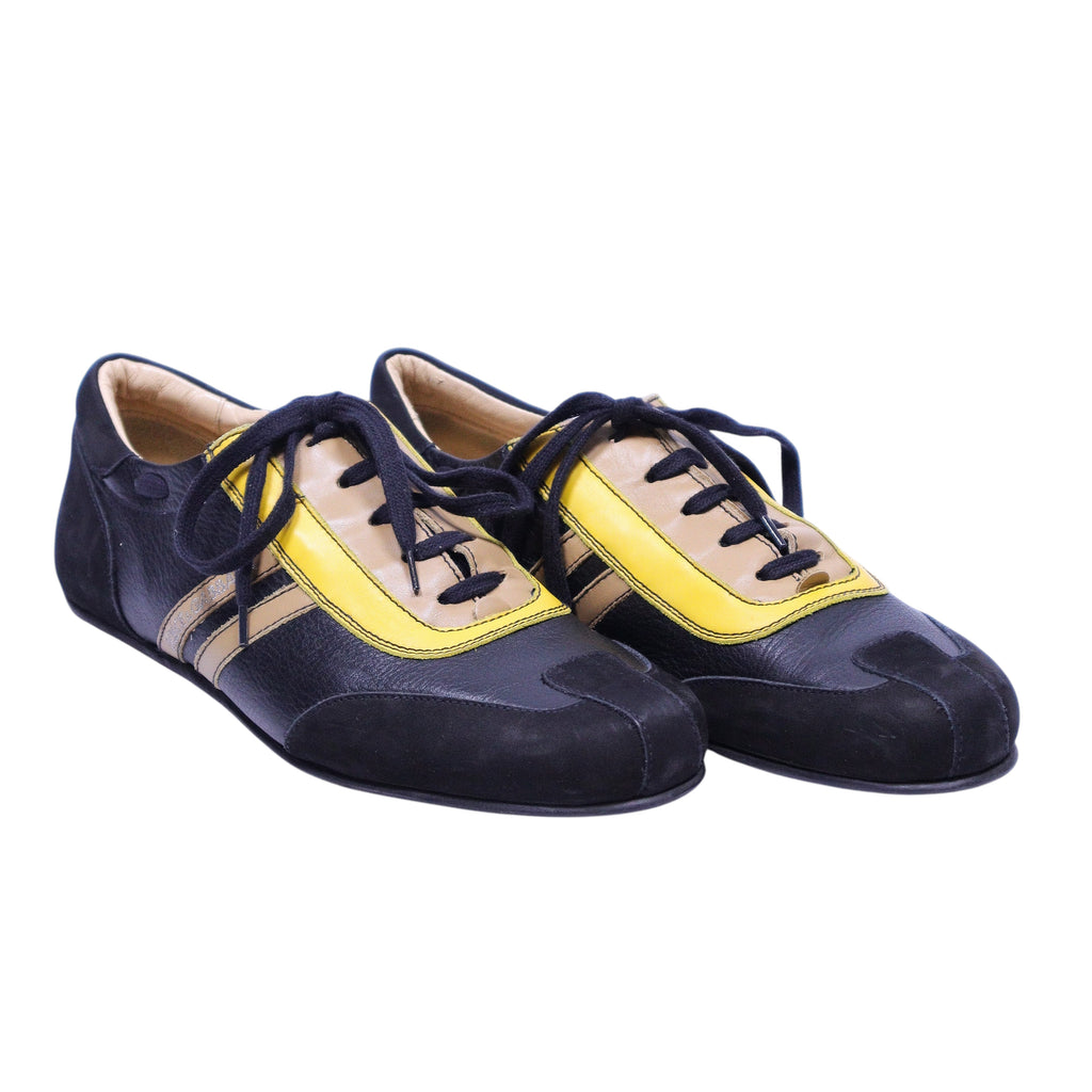 A pair of Dolce Gabbana black and yellow sneakers with laces. Vintage Dolce & Gabbana low-top lace-up sneakers in black with yellow and taupe panels; mixed-material upper with contrast stripes, rounded toe, and retro racing/bowling vibe—designer, rare.