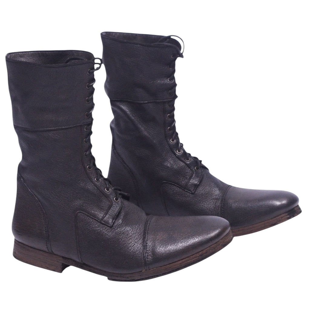 A pair of dark brown leather boots with a lace-up front and a low heel on a plain background. Christian Peau dark brown leather lace-up boots with a mid-calf shaft, round cap toe and low stacked heel. Grained leather with vintage, rugged patina; artisanal, designer, rare.