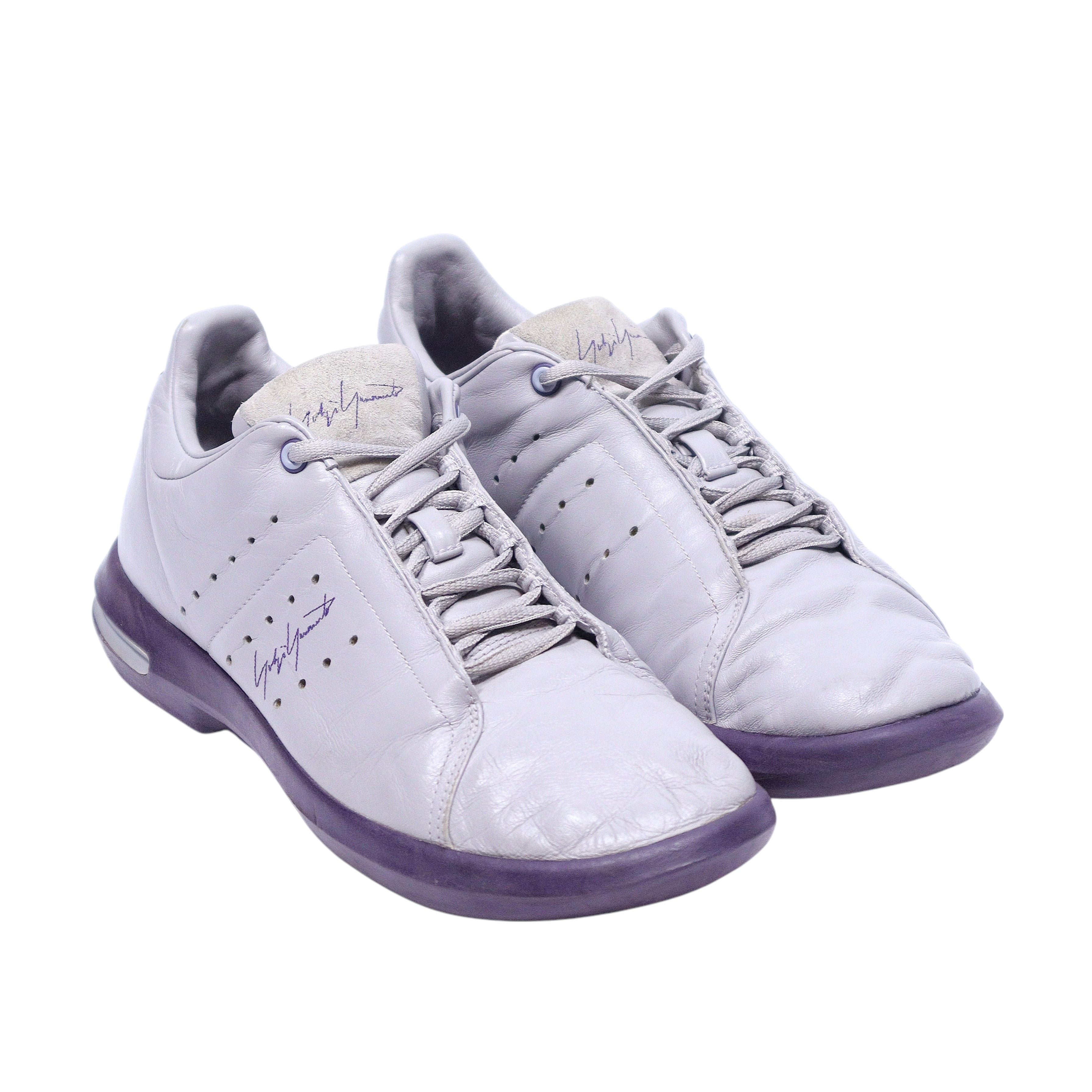 A pair of Yohji Yamamoto adidas sneakers with gray and purple color scheme. Yohji Yamamoto x adidas 2002 gray leather sneakers with purple sole, perforations, lace-up front, and signature detail.