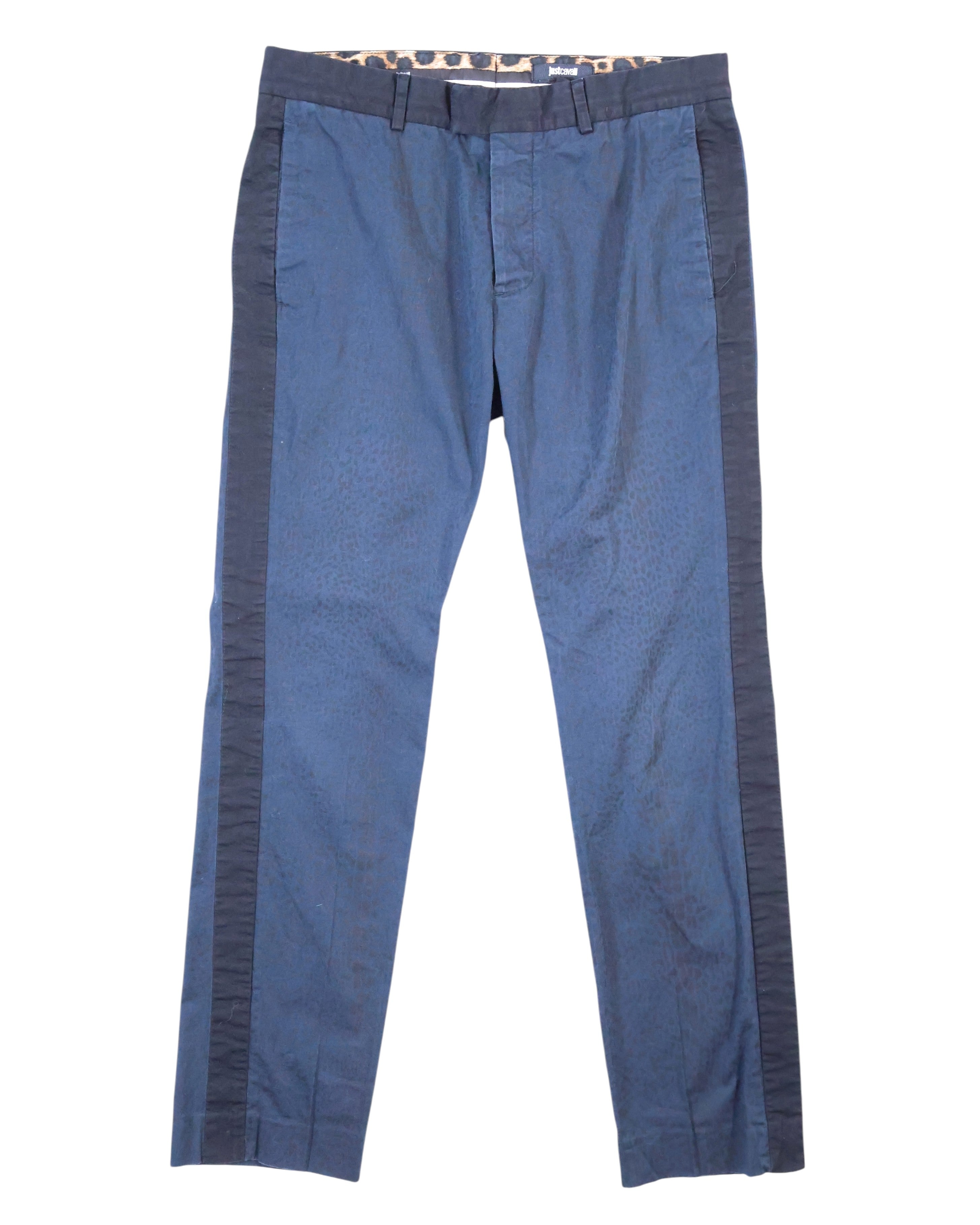 A pair of dark blue trousers with a subtle leopard pattern on the sides, displayed flat on a white background. Roberto Cavalli dark blue trousers with a subtle leopard print and contrast side stripes, straight-leg cut with belt loops, side pockets and a zip fly. Smooth woven fabric with a clean finish; vintage designer piece, rare and unique.