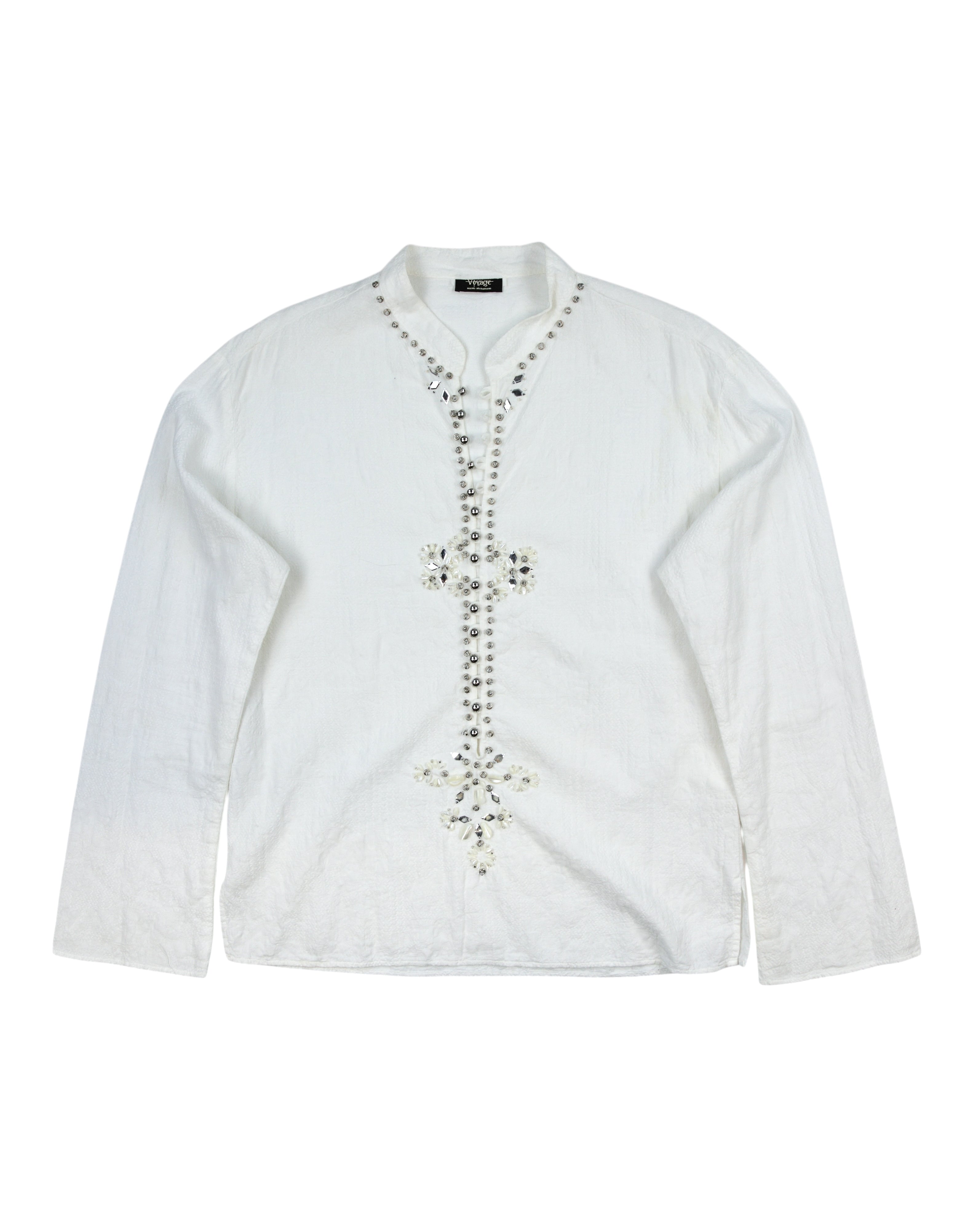 Voyage Mazzilli & Michielsens white/ivory long-sleeve shirt; band collar with notched V, textured cotton/linen feel; hand-embellished beaded/crystal floral placket in a vertical motif; relaxed easy fit, unisex; style with jeans, tailoring, leather; tags: boho, rock, festival, Y2K, romantic; Voyage (Europe, boutique studio craft, small-batch), collectible.