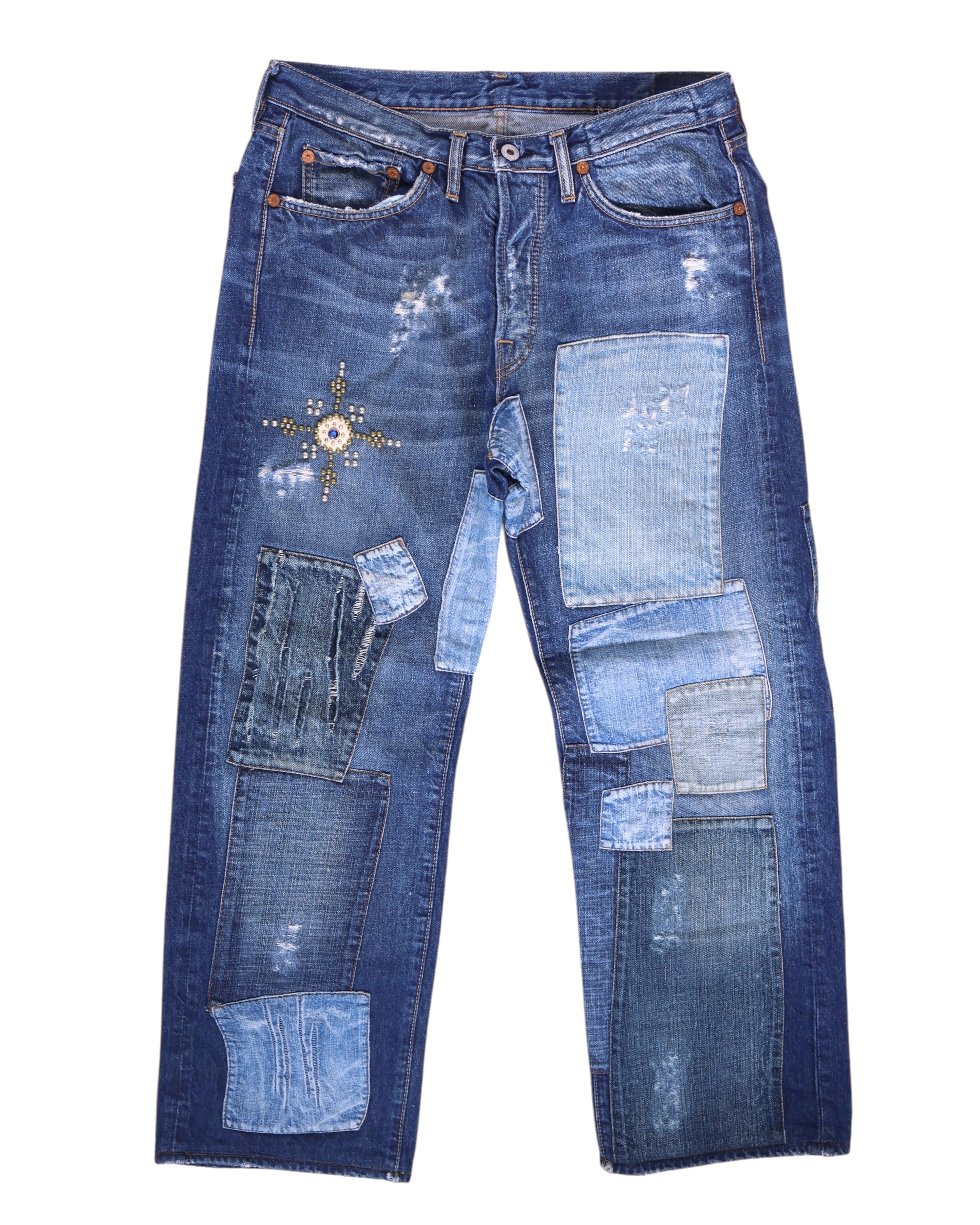 Vintage Ra-re medium-blue patchwork jeans/denim trousers featuring multi-shade repair panels, distressed wear and a studded star motif at the thigh; mid-rise straight leg with five pockets and button front. Luxury designer, rare and unique, laid flat on white.
