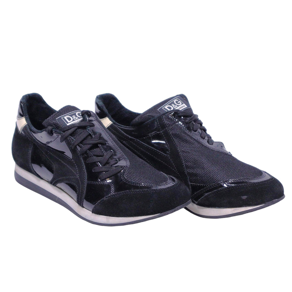 A pair of Dolce Gabbana leather suede sneakers in black color. Vintage D&G Dolce & Gabbana black low-top sneakers/trainers with mixed materials—smooth leather, suede and glossy patent overlays—mesh panels, lace-up front, logo tongue, gold heel tab, retro runner silhouette and cushioned white/black sole.