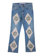 A pair of jeans with stone embroidery design, featuring diamond-shaped patches on the legs. Vintage Voyage Mazzilli Michielsens light-blue jeans/denim trousers with ivory diamond panel appliqués set with stone-like embellishments and studs; mid-rise straight leg, five-pocket button waist with gentle fading—luxury, rare, unique, laid flat on white.