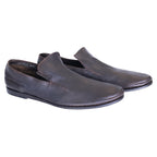 A pair of brown leather loafers on a white background. Vintage Dior brown leather loafers in a minimalist slip-on/moccasin style with rounded toe, low stacked sole, and gentle patina—refined, rare luxury.