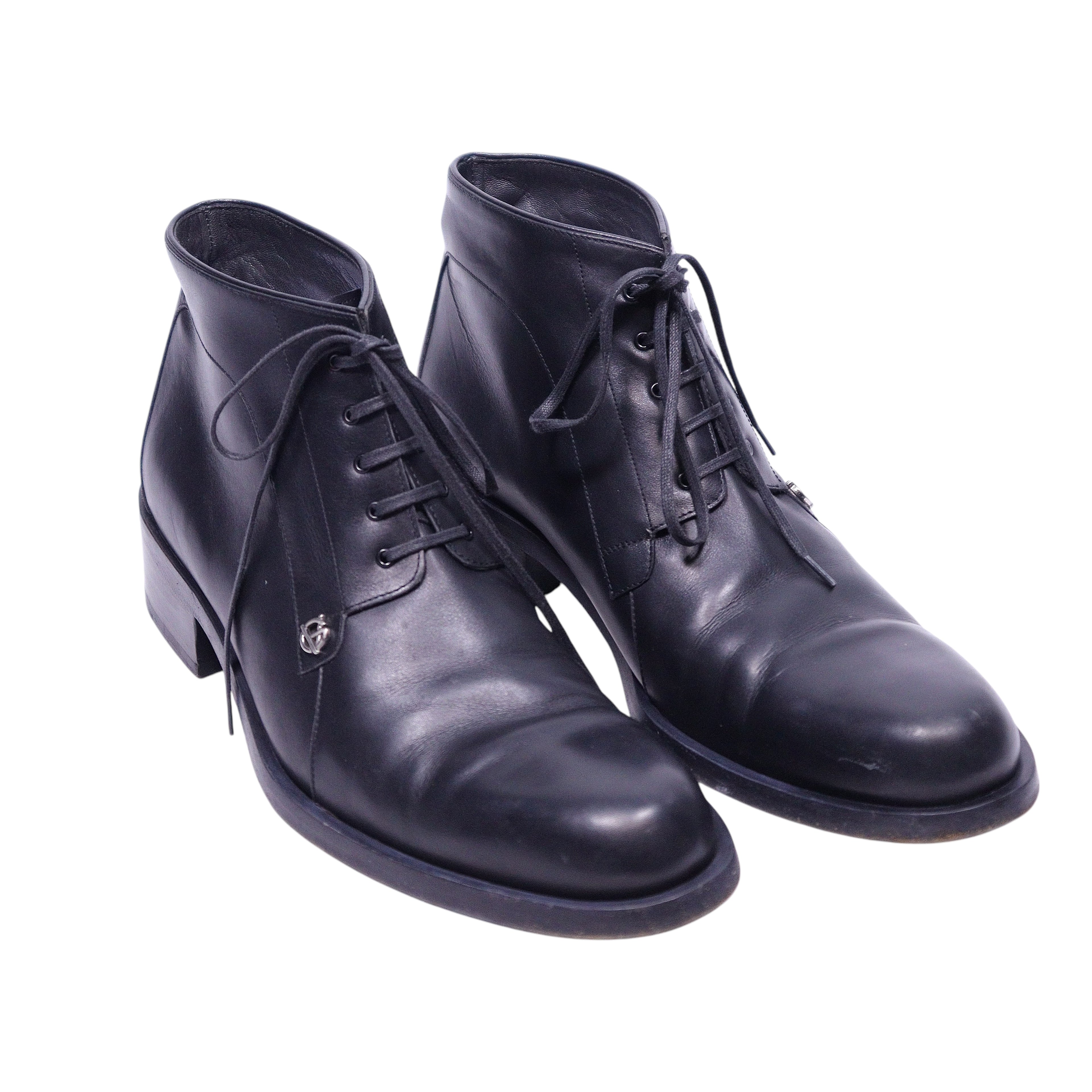 A pair of black leather boots with laces and a low heel.Gianni Versace black leather lace-up ankle boots with a clean round toe, five-eyelet closure and a low stacked heel. Smooth polished finish with a subtle logo charm; vintage, luxury, rare.