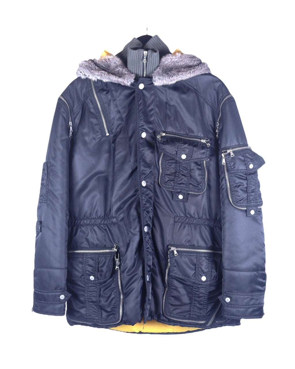 A Dolce & Gabbana black coat with rabbit fur on the hood, multiple pockets, and a zipper closure. Dolce & Gabbana navy/black nylon parka coat with rabbit-fur hood trim; insulated shell, rib-knit stand collar insert, multi cargo pockets, zip/snap front, silver-tone hardware, contrast yellow lining; regular fit, unisex; winter, streetwear, denim; style tags: utility, military, Y2K; brand context: Italian luxury house, Made in Italy craft.
