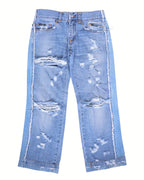 Vintage Dolce & Gabbana Silver Label light-blue jeans/denim trousers with heavy distressed, ripped and shredded details, whiskering and fading; straight-leg, mid-rise five-pocket design with belt loops, button front, contrast side panels and raw frayed hems. High-end, rare designer pair laid flat on white.