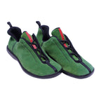 A pair of green suede trainer shoes with black and red accents. Prada green suede low-top trainers with black piping, bungee lace system, red tongue pull tab, and black rubber sole.