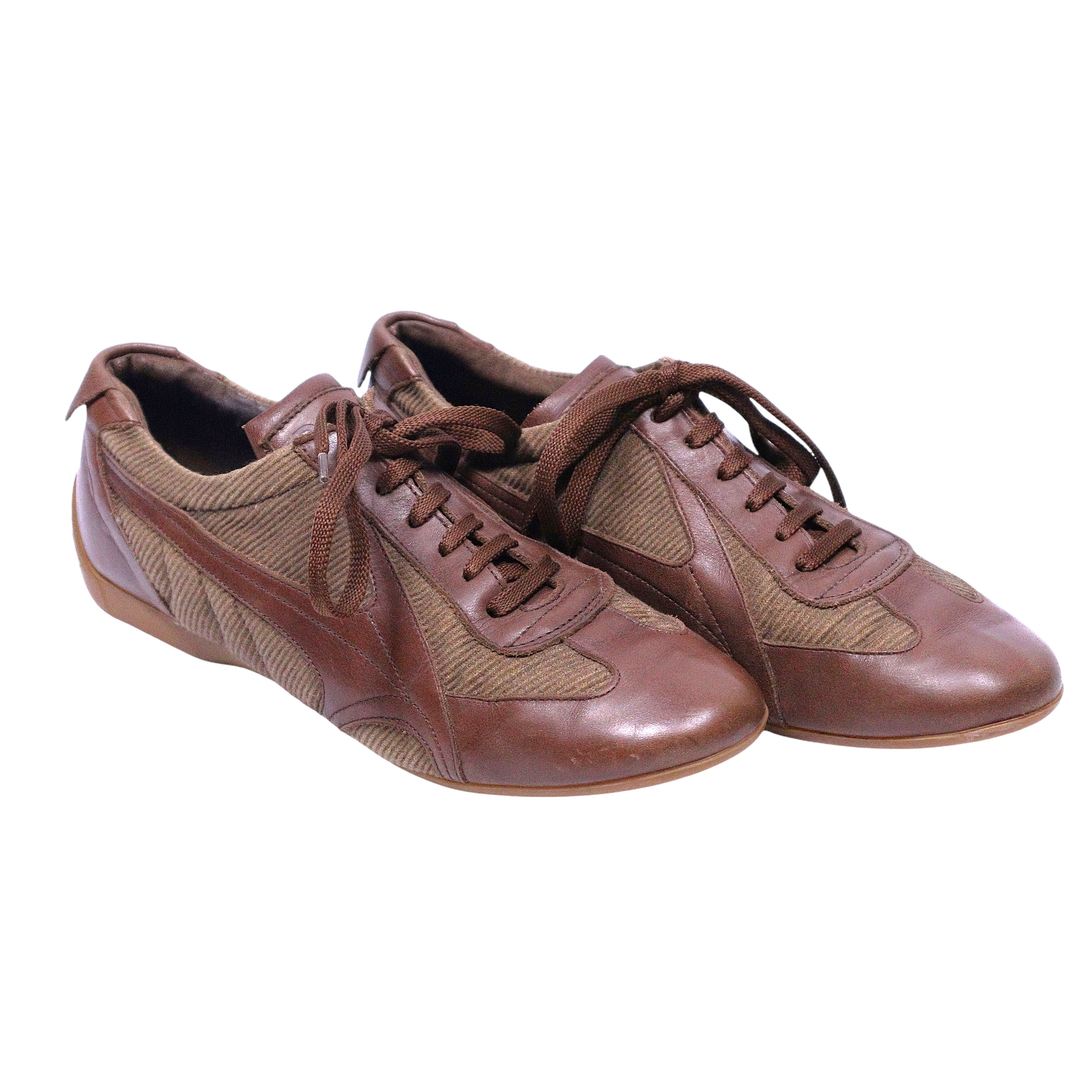 A pair of brown Dolce Gabbana leather sneakers with lace-up closure. Dolce & Gabbana brown leather low-top sneakers with textile/mesh panels, lace-up vamp and slim rubber sole. Sleek retro trainer with rounded toe; vintage, Italian, rare.