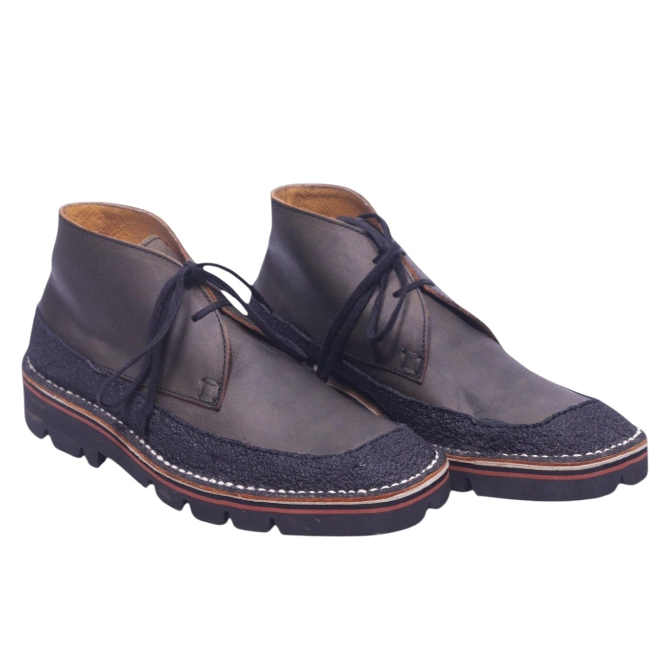 A pair of Issey Miyake brown chukka boots with lace-up closure and a rubber sole. Issey Miyake brown chukka/ankle boots in smooth leather with textured fabric trim, moc-toe apron stitching and open lacing. Thick contrast welt and lug sole; vintage designer, rare.