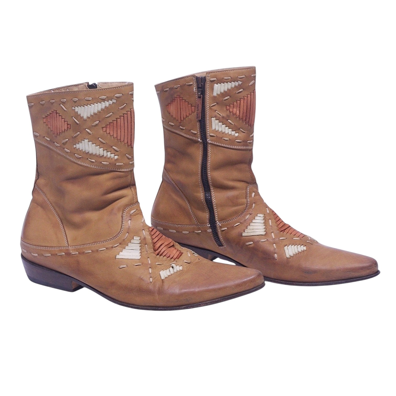 A pair of tan beige leather boots with geometric stitching details and a side zipper. Roberto Cavalli tan-beige leather western santiag boots with geometric contrast stitching and woven details, pointed toe, side zipper, and low stacked heel.