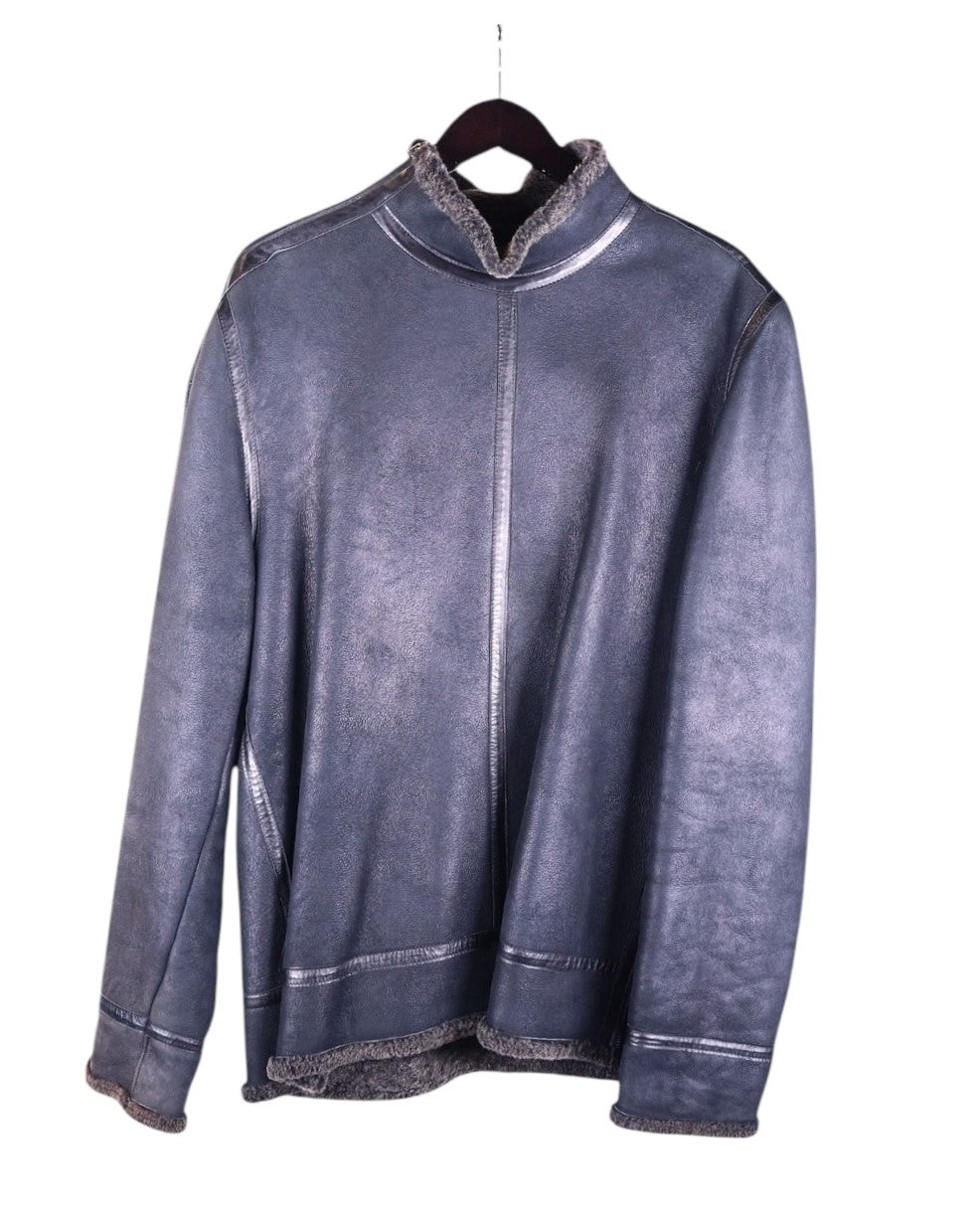 A Bill Tornade leather pullover with wool lining, displayed on a hanger, predominantly dark colored with a textured surface. Vintage Bill Tornade French designer shearling pullover—steel-grey/charcoal genuine sheepskin leather with plush wool/fleece lining; mock-neck/stand collar, raw-edge exposed shearling at cuffs and hem, clean panel seams; relaxed over-the-head anorak/overshirt silhouette, cozy winter-ready insulated outerwear; Paris fashion house heritage; unisex statement layer.