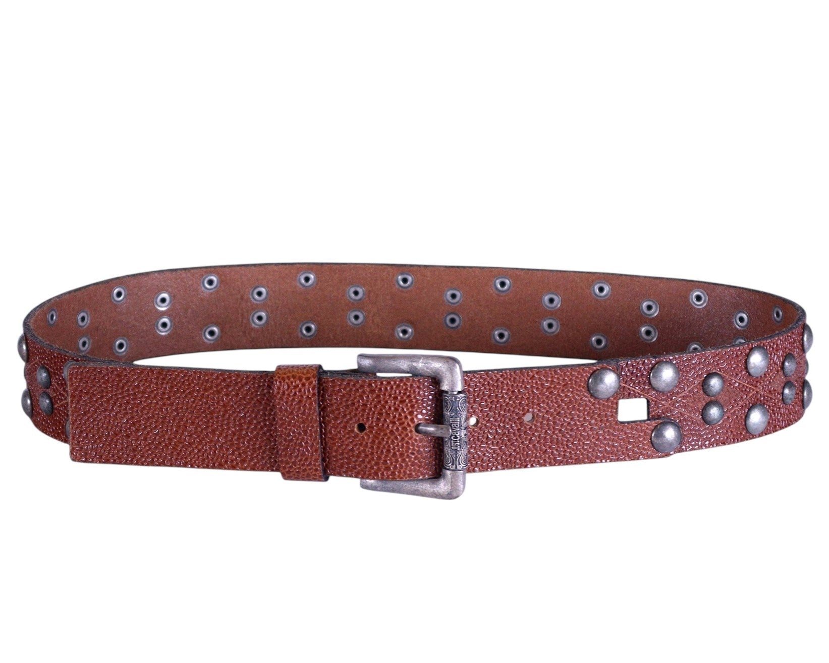 A brown studded leather belt with a metal buckle. Just Cavalli tan/cognac brown grained leather belt; studded strap with dome rivets and grommeted lining, square-punch accent, aged silver metal buckle and keeper; unisex; pairs with denim, cargos, tailoring; tags: rock, biker, Y2K, streetwear; brand context: Italian luxury diffusion by Roberto Cavalli; vintage, rare.