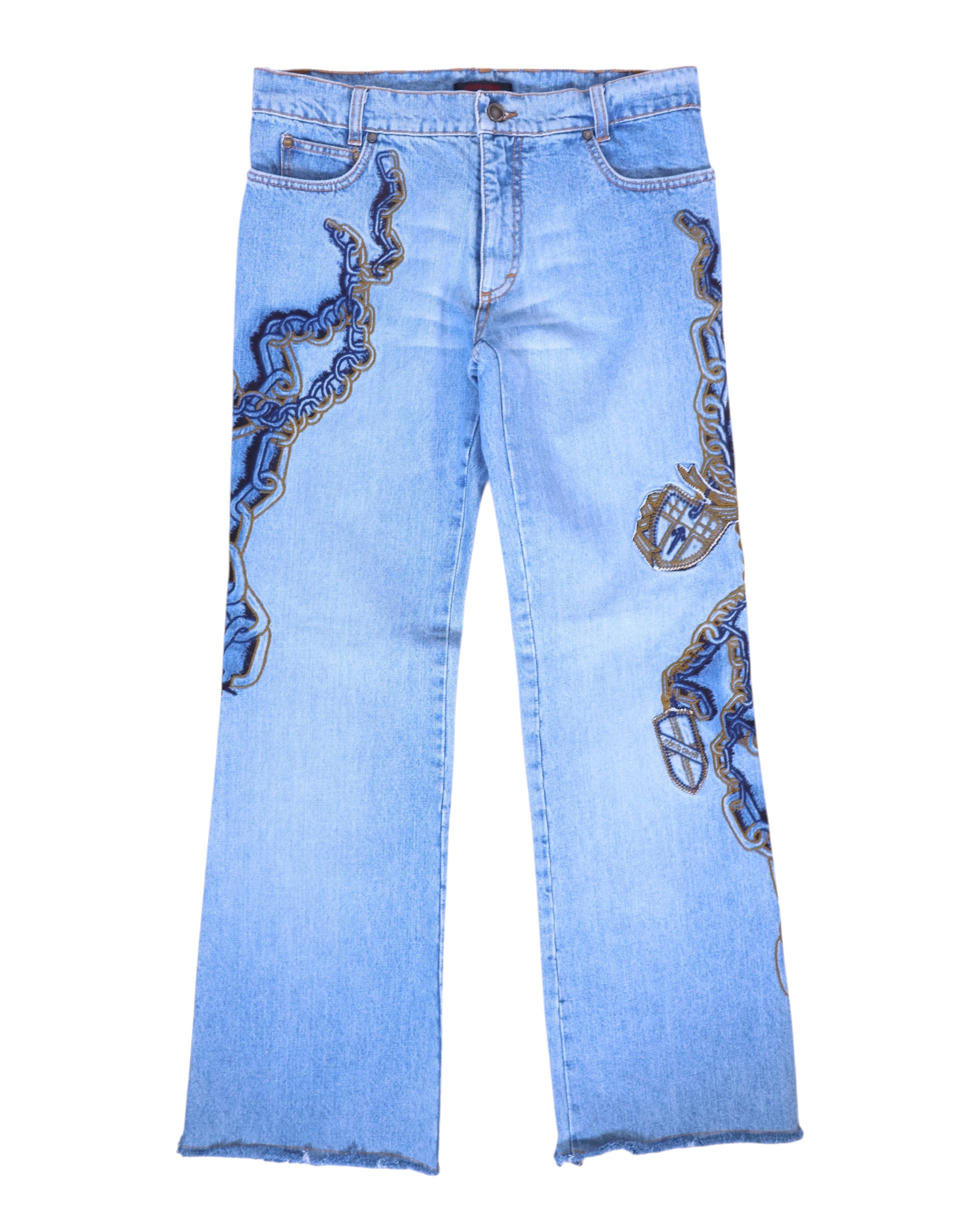 A pair of blue jeans with intricate chain embroidery detailing. Light-wash denim jeans with bold chain embroidery in navy and gold winding along the legs, five-pocket design with belt loops and zip fly. Straight leg with raw, frayed hems; vintage designer, rare statement denim.