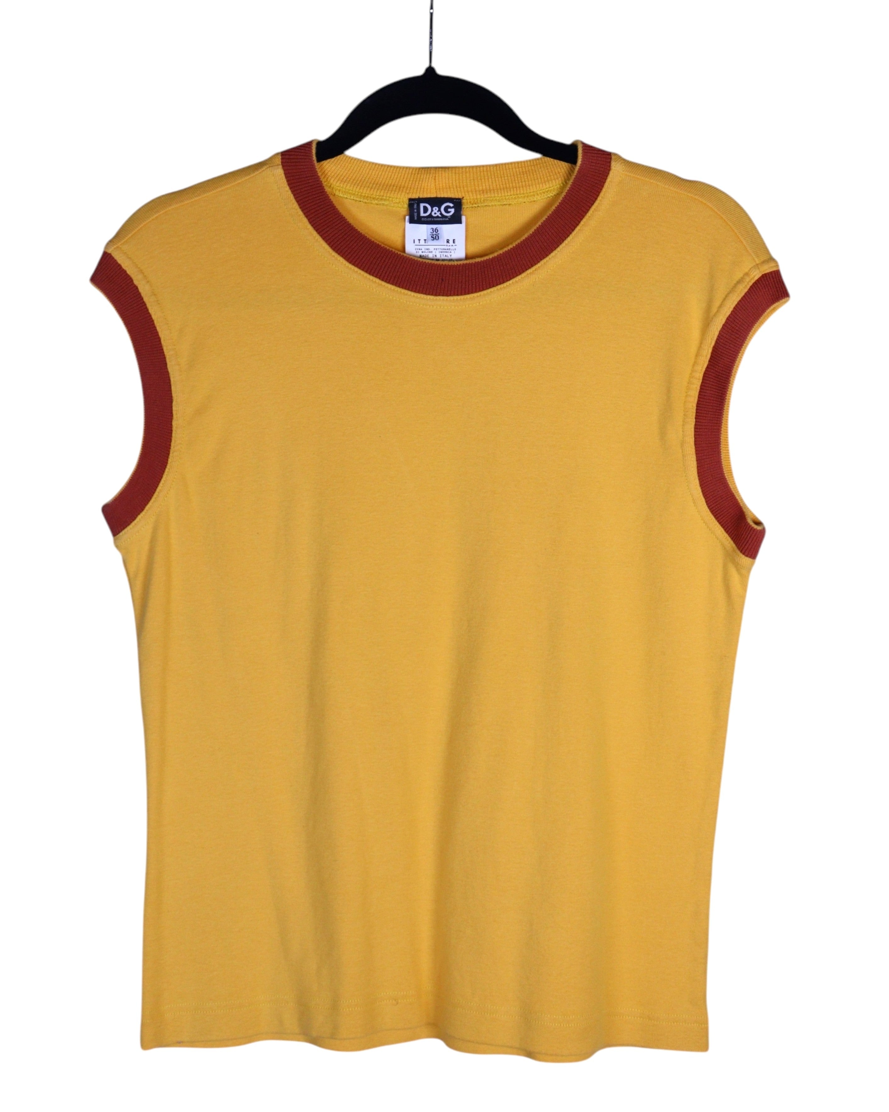 Yellow sleeveless shirt with red trim on a hanger against a white background. Vintage D&G Dolce & Gabbana mustard/yellow sleeveless T-shirt / tank / muscle tee / vest in soft cotton jersey; contrast burgundy/brick-red rib crewneck and armholes; minimalist solid color, fitted casual athleisure top; Italian designer brand from Milan (Italy), early-2000s/Y2K vibe; unisex layering shirt for streetwear or summer looks.