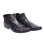 A pair of black leather boots with a pointed toe and visible stitching. Roberto Cavalli black leather ankle boots with elastic paneling, sleek almond toe, and low stacked heel.