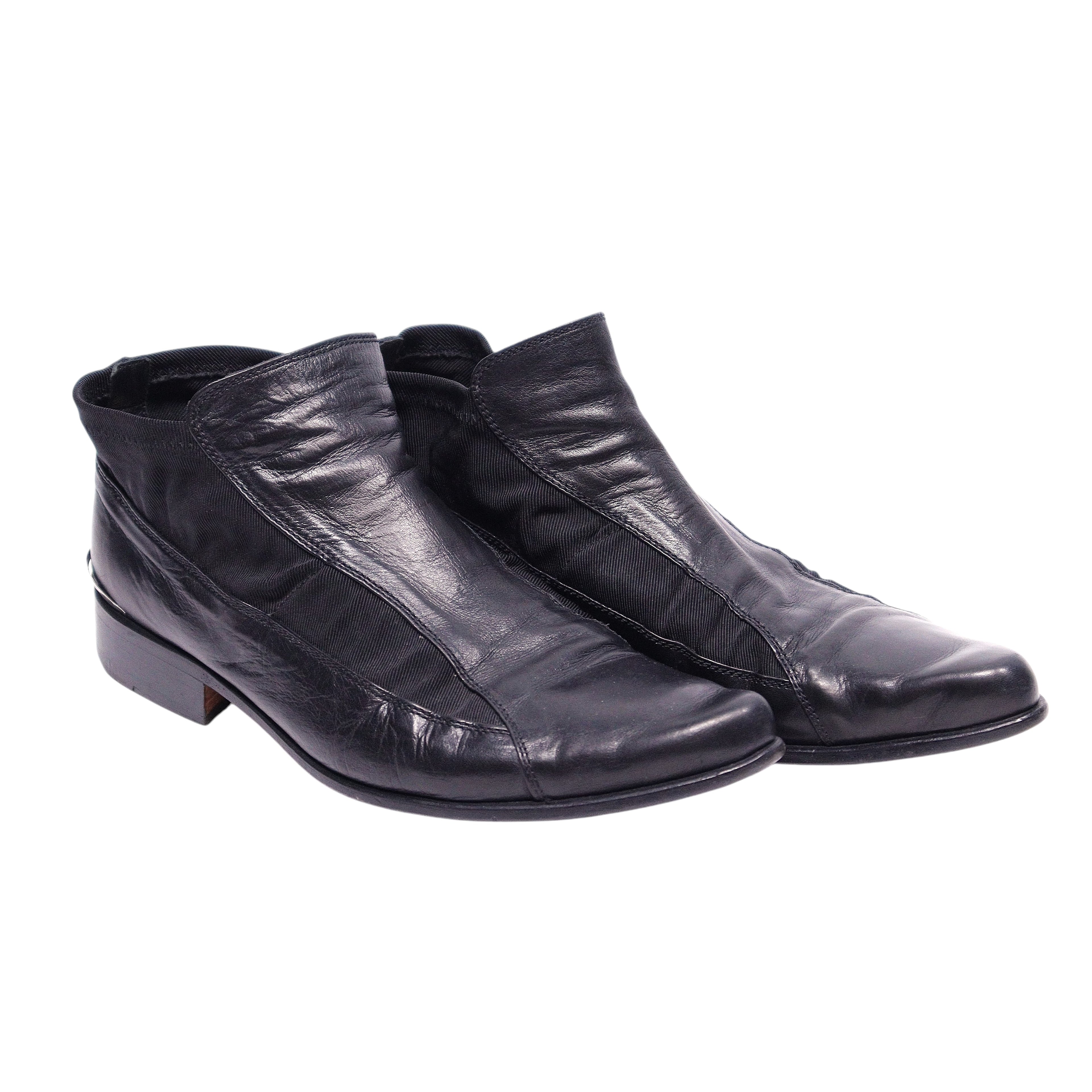 A pair of black leather boots with a pointed toe and visible stitching. Roberto Cavalli black leather ankle boots with elastic paneling, sleek almond toe, and low stacked heel.