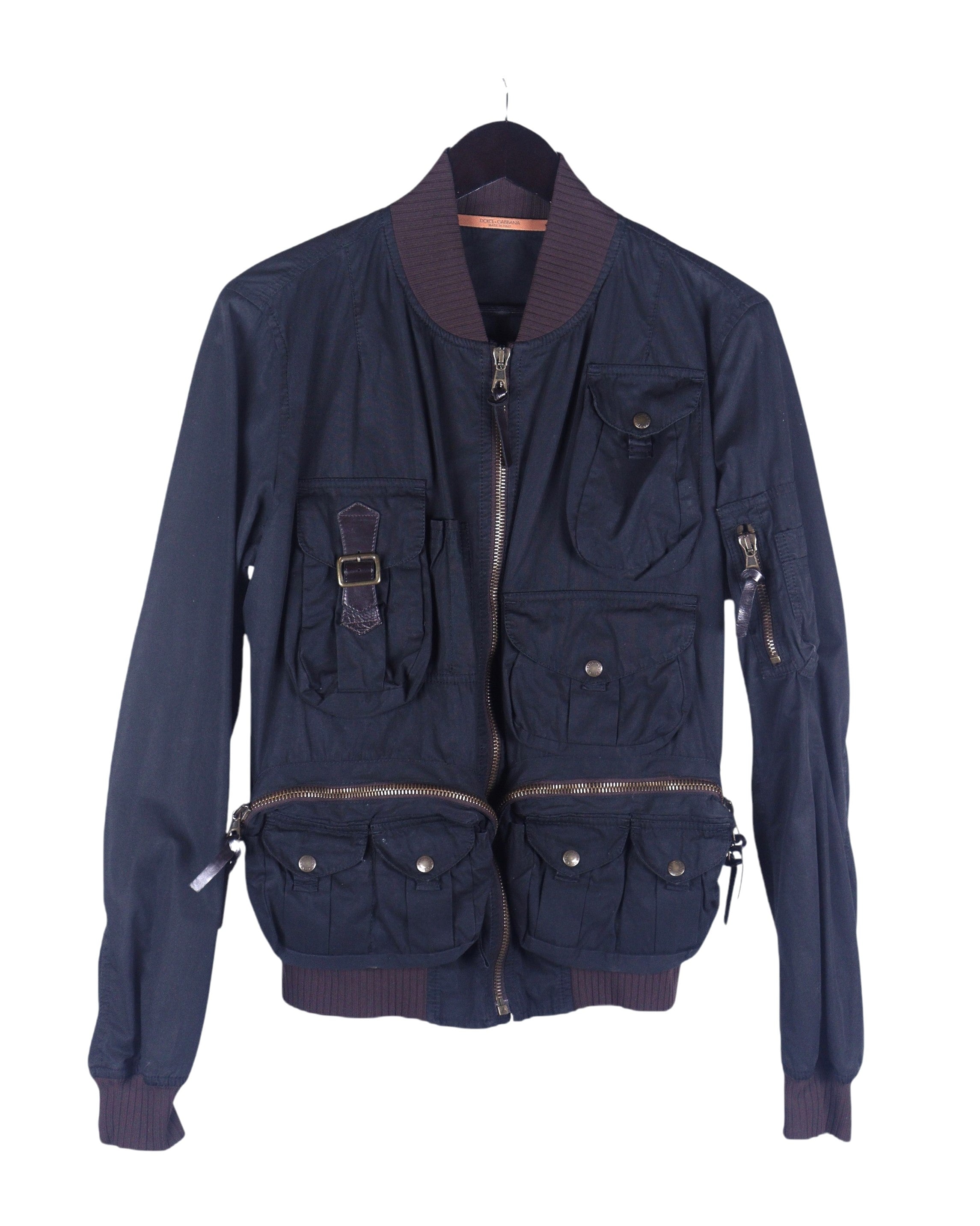 Dolce & Gabbana (D&G) utility bomber jacket / flight jacket / aviator—dark navy/black cotton-blend twill, zip front, ribbed stand collar, cuffs and hem, sleeve zip pocket, multiple cargo/patch pockets with snaps and zips; field-jacket meets bomber silhouette, workwear/military-inspired streetwear layer; Italian luxury brand from Milan, known for high-quality tailoring and craftsmanship; unisex styling over tees or knitwear, great for everyday, travel, festival, or city wear.