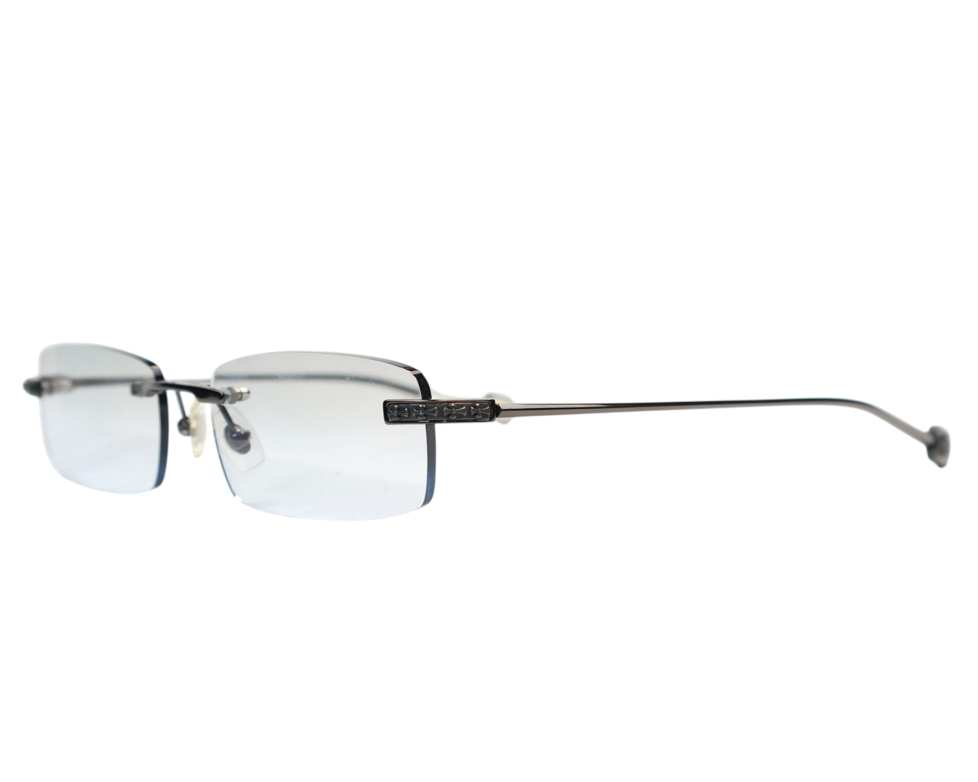 Chrome Hearts “Generator II” rimless / semi-rimless rectangle eyeglasses frame — handmade in Japan for the Los-Angeles luxury label; slim metal bridge with adjustable nose pads, narrow micro-rectangular lenses, black/gunmetal temples with signature carved Chrome Hearts cross hardware and gothic detailing, lightweight minimalist design, unisex Y2K/2000s aesthetic; rare collectible optical frame, prescription-ready, premium artisanal Japanese craftsmanship.